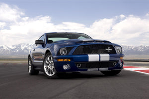 Blå Ford Mustang Shelby GT500 med vita racingränder på en racerbana