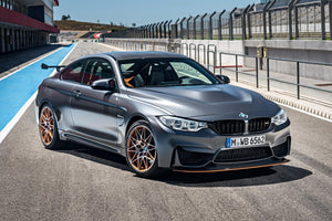 Grå BMW M4 med guldfärgade fälgar i depån på en racerbana